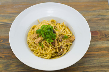 Creamy spaghetti with chicken and mixed mushrooms. Sprinkled with spring onions cut into rings. Freshly prepared and served as a healthy and fast meal of Italian cuisine.