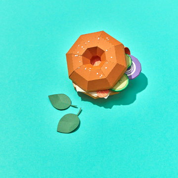 Handcraft burger made from paper pieces of tomato, cucumber, cheese and sausages with mint leaves on a blue background with copy space. Flat lay