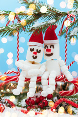 Two lovers of Marshmallow snowmen are sitting on a swing of candy. Christmas meeting a couple in love concept.