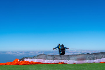 Paraglider preparing full flight equipment and paragliding soaring in the beautiful blue sky and bright sunny day on the mountain.Extreme Sport,Travel Holiday Vacation Concept.