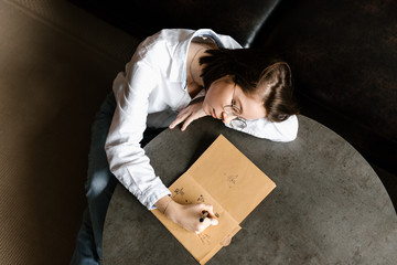 Dreamy girl drawing in notepad