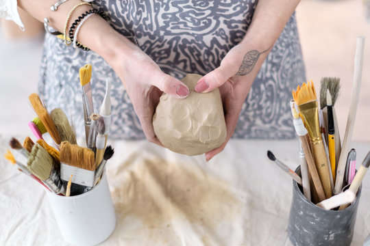 Female potter works with clay, craftsman hands close up, kneads and moistens the clay before work