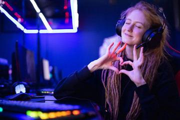 Streamer beautiful girl shows heart sign with hands professional gamer playing online games computer, neon color - obrazy, fototapety, plakaty