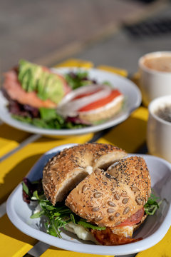 A loaded everything bagel sandwich on a yellow table