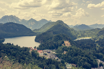 Picturesque view of Bavarian castle with lake surrounded with forest.