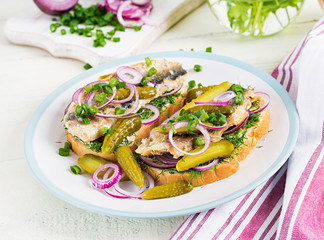 Traditional Dutch sandwich with herring and pickles cucumbers on white table. Smorrebrod.