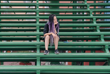 Young cool woman alone on a stadium bench
