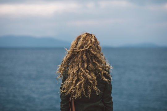 Curly woman shot from behind staring at the sea