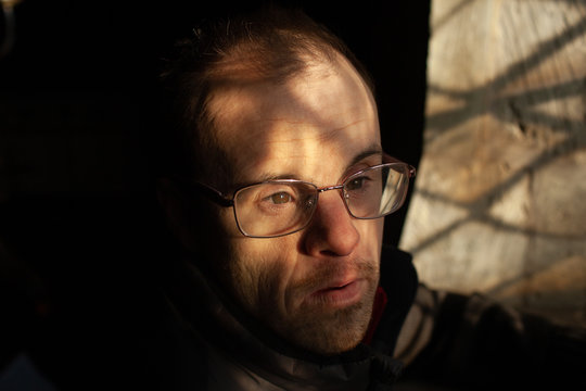 Close portrait of a middle aged man with Down's syndrome standing by a window in an old church.