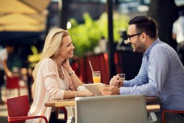 Cheerful couple having fun while using touchpad in a cafe.