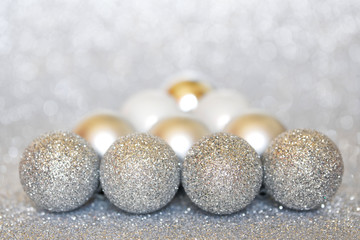 Shiny Christmas tree decorations lie on a silver sparkling surface. Happy New Year and Merry Christmas. Bokeh