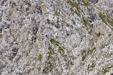 Three people climbing on a limestone wall with wide valley on the background. Mountain background.                     
