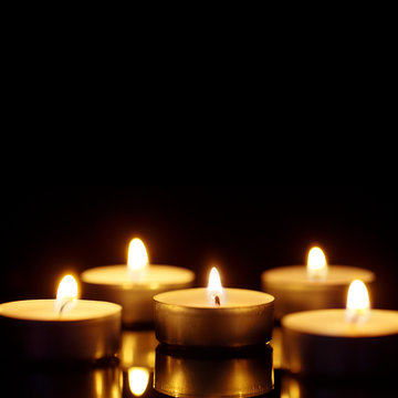 Burning candles with copy space on black background, shot with shallow depth of field