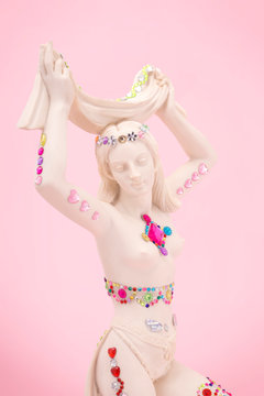 White statue of a woman decorated with shiny stickers.