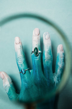 Painted hand in rings through magnifying glass