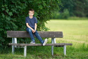 The boy relaxing on a bench in the field