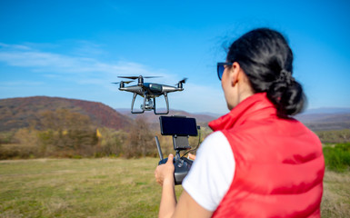 A woman is piloting a drone driving it from a remote control.