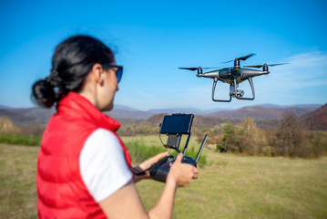 A woman is piloting a drone driving it from a remote control.
