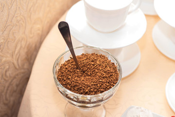 Instant coffee in a glass bowl on a background of white coffee cups