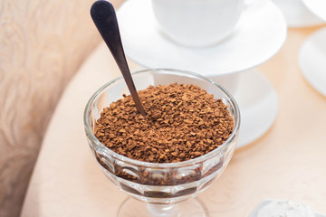 Instant coffee in a glass bowl on a background of white coffee cups