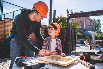 The father teaching his son to use hammer and nails