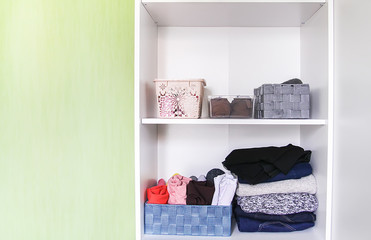 Different clothes in home wardrobe. Small space organization. Vertical storage.