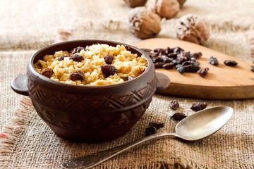 Sweet millet porridge with dark raisins in ceramic rustic bowl