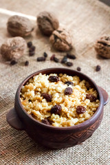 Sweet millet porridge with dark raisins in ceramic rustic bowl