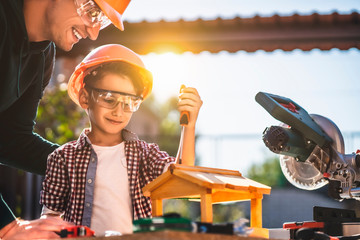 The father and his little son making a wooden bird feeder