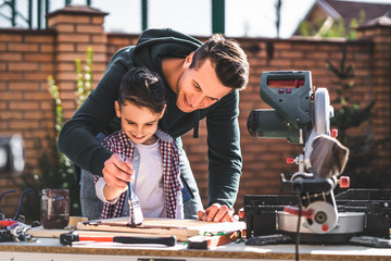 The father and son paint carpentry with one brush together