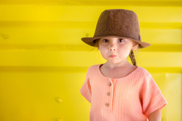 Portrait of happy cute emotional little girl in rural style brown hat and muslin clothes in a...