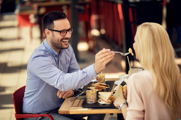 Happy couple sharing food and having fun during lunch in a restaurant.