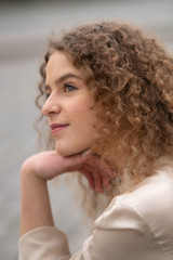 Profile view of young woman with curly hair resting her head on her hand