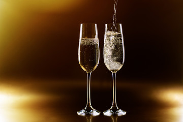 Two glasses of champagne on golden background.