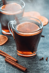 Christmas traditional hot beverage mulled wine with spices and orange slices in a glass cups on a table.