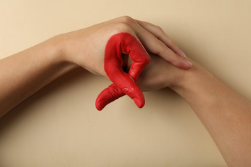 Two hands depict AIDS awareness sign on beige background, copy space