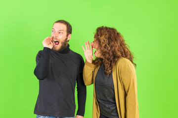 Young beautiful couple over green background, mad, shouting and yelling with aggressive expression.Frustration and crazy concept.