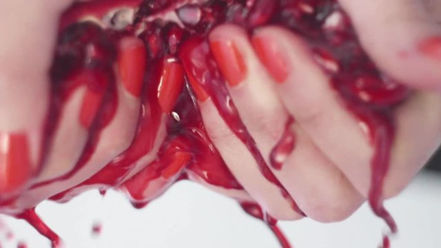 melograno succoso spremuto da mani di donna con smalto rosso