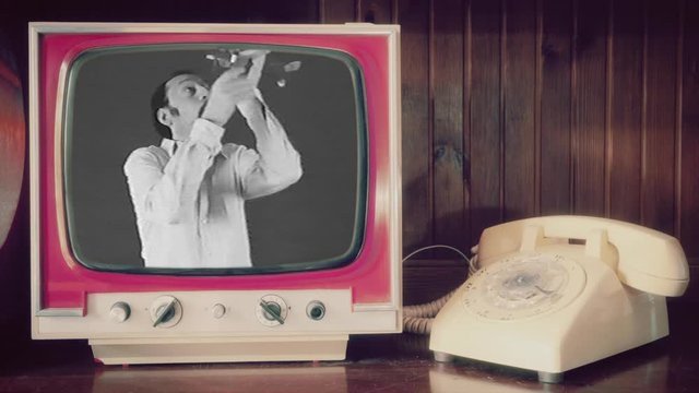 Analog scene (rotary phone, vintage TV): an adult man having fun playing with a plane toy. Funny cringey situation.