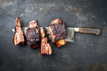 Barbecue burnt chuck beef ribs with hot rub as top view on a knife on a rustic board