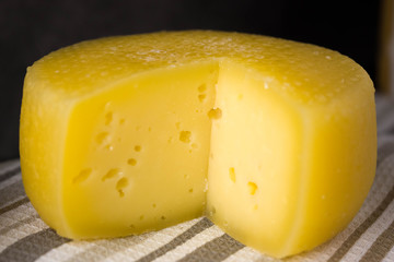 Cheese wheel with a cut piece on a striped towel