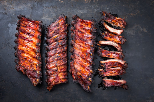 Barbecue pork spare ribs St Louis cut with hot honey chili marinade as top view on an old rustic metal board with copy space
