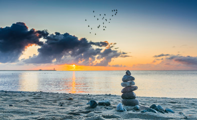 stos kamieni  na plaży o wschodzie słońca - obrazy, fototapety, plakaty