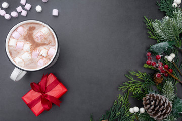 Hot chocolate mugs with marshmallows and christmas gift boxes. Flat lay with fir branches. Gray background. Copy space.