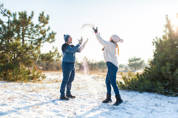 Loving couple play snowballs in winter in the forest. Throw each other snow. Laugh and have a good time