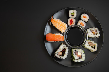 Sushi on black dish isolated on black background with copy space. Top view.