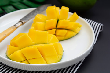 Sliced mango fruit on a white round plate ready to be served. Top view, healthy fruit breakfast or snack.