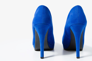 Close up blue pair of women shoes. Backside view of fashion female high heels isolated on white background. Woman footwear on the floor. Selective focus