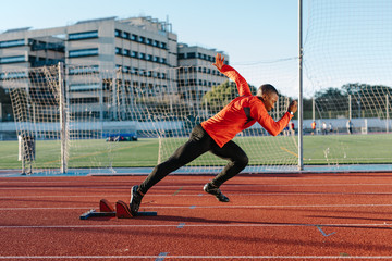 Black athlete sprinting from starting blocks
