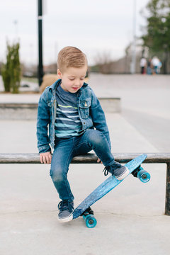 Cute young boy sitting on a railing in a skatepark